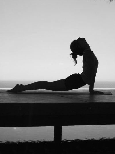 Woman in black doing yoga with gray backrgound
